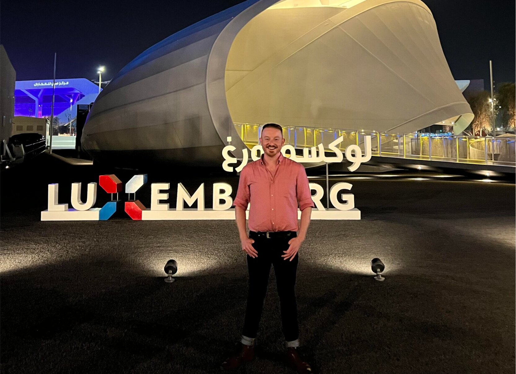 Daniel Atz in front of the Luxembourg pavilion sign at night